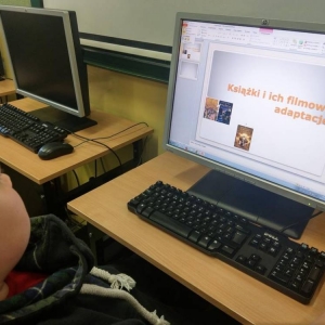 Uczeń siedzi przed monitorem komputera, na którym wykonuje prezentacje multimedialną
