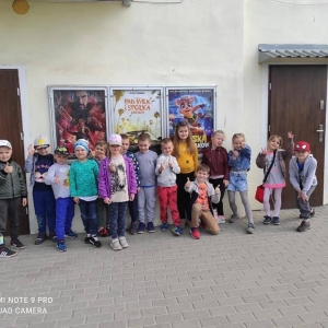 Fot. K. Gątarz, Kino Grunwald w Olsztynku.  Na zdjęciu grupa dzieci 5 – 6 letnich stojących przed budynkiem kina w Olsztynku. W tle plakaty reklamujące repertuar kina.
