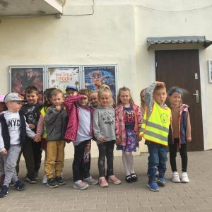 Fot. M. Trochim, Kino Grunwald w Olsztynku.  Na zdjęciu grupa dzieci 4 – 5  letnich stojących przed budynkiem kina w Olsztynku. W tle plakaty reklamujące repertuar kina.