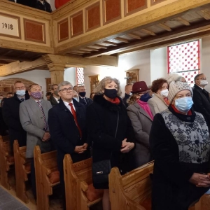 Liczna grupa uczestników mszy (zaproszeni goście) stoi przy ławkach w kościele