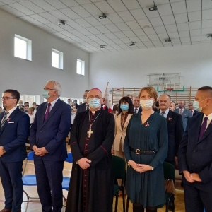 Zebrani stoją w sali gimnastycznej, na przedzie dyrektor, W-M kurator Oświaty, Arcybiskup, zastępca Burmistrza i Starosta Olsztyński