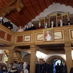 Uczestnicy mszy stoją zwróceni w stronę ołtarza.