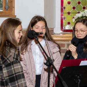 Trzy uczennice śpiewają w kościele do mikrofonu
