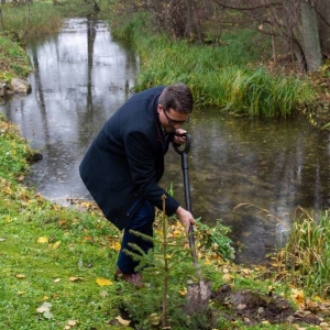 Moment sadzenia drzewka przez Dyrektora, w tle rzeka