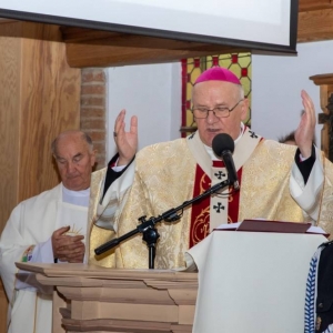 Arcybiskup prowadzi mszę, po jego lewej stronie stoi ksiądz, a po prawej strażak w mundurze