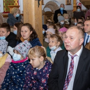 Liczna grupa dzieci i dorosłych siedzi na ławkach w kościele