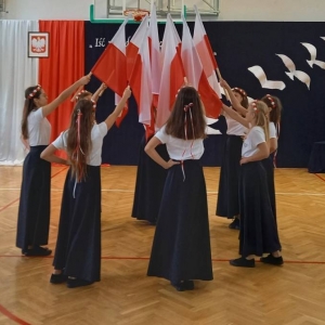 Taniec z flagami – 8 uczennic stoi po kole, w którego centrum łączą uniesione nad głowami flagi