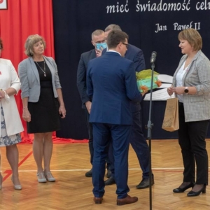 Dyrektor przyjmuje upominek, Przy nim stoi dyrekcja szkół gminnych i ZASiP w Olsztynku
