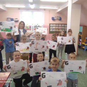 Na zdjęciu grupa dzieci trzymających obrazki z bohaterami z bajek.