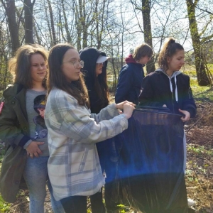 Siódmoklasiści sprzątają teren zielony nad rzeką w okolicy szkoły.