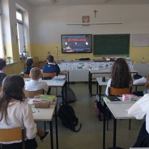Siódmoklasiści, podczas zajęć biologii, siedzą w ławkach i oglądają wyświetloną na telewizorze interaktywnym tematyczną prezentację multimedialną.