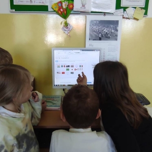 Czworo drugoklasistów przy komputerze oglądają w Internecie flagi różnych państw.