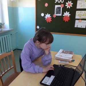Piątoklasistka podczas zajęć historii stoi przy biurku i wykonuje tematyczne ćwiczenia online na laptopie.