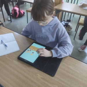 Piątoklasistka podczas zajęć matematyki siedzi w ławce i wykonuje ćwiczenia online z wykorzystaniem aplikacji WordWall.