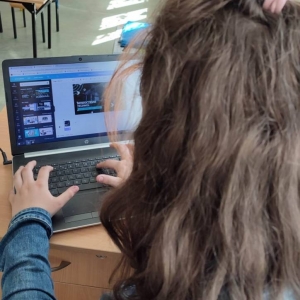 Siódmoklasistka siedzi przy biurku i w programie Canva przygotowuje materiał audio-wizualny na temat nowych technologii.