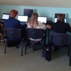 4 ósmoklasistów, w pracowni komputerowej, siedzi przed laptopami i rozwiązują zadania pracy klasowej, przygotowanej online w aplikacji Forms.