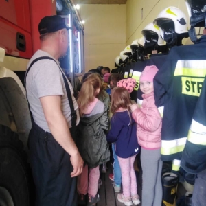 Przedstawiciele OSP oprowadzają dzieci wokół wozu strażackiego.